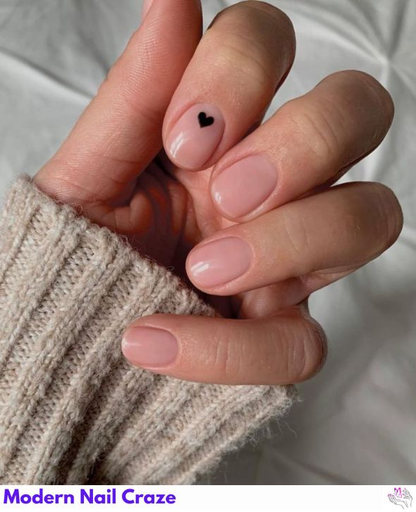 Nude nails featuring a simple black heart design.