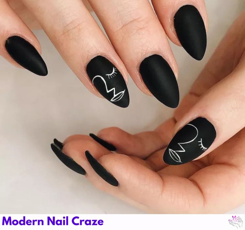 Artsy matte black nails with design featuring abstract faces.
