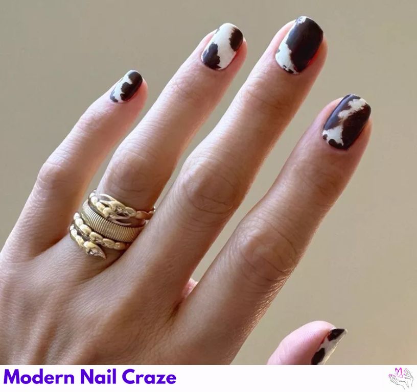 Artsy cowhide nail design with abstract monochrome patches.