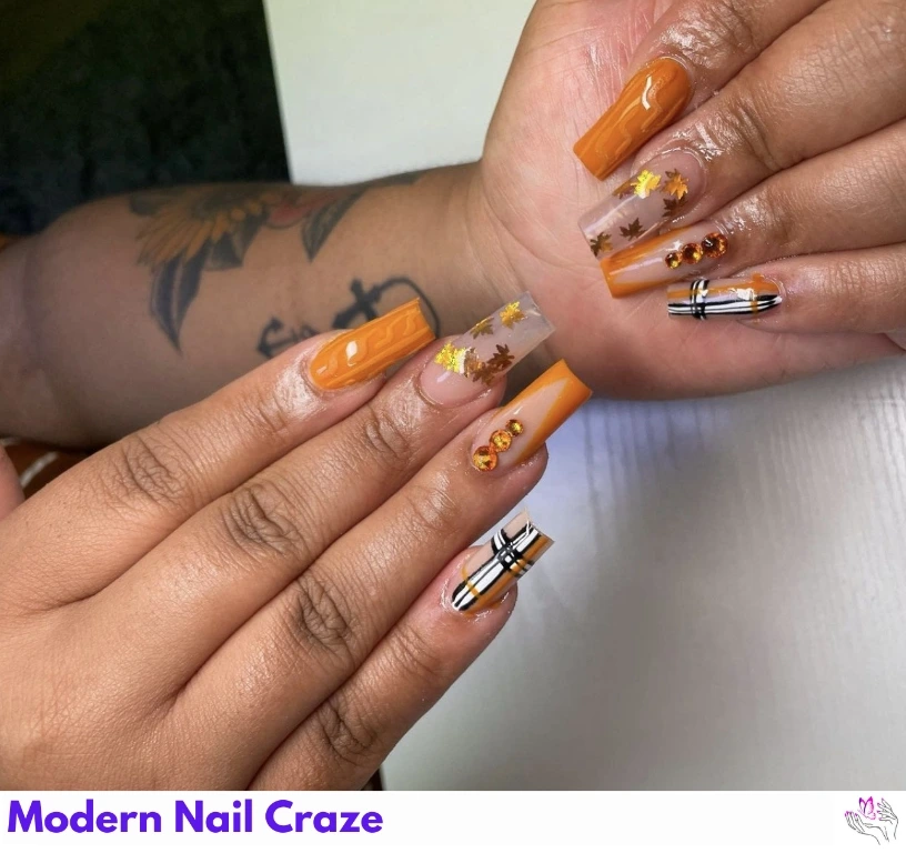 Fall foliage nails with painted maple leaves in orange, red, and gold.