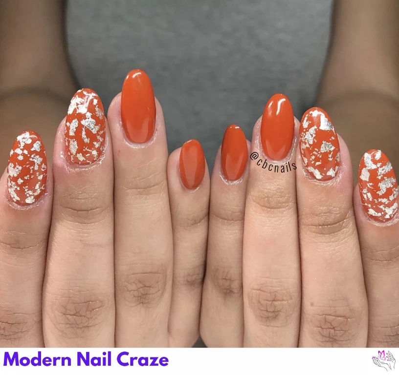 Burnt orange almond nails with gold flake accents for a fashionable fall look.