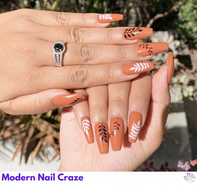 Burnt orange nails with dried floral and natural woodgrain-inspired nail art.