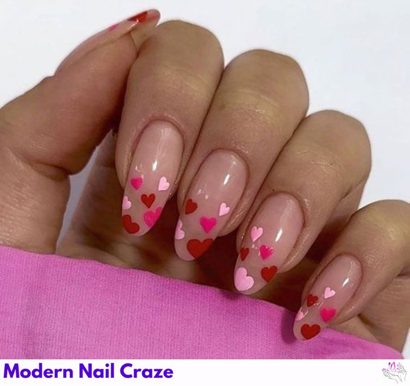 Baby pink nails with red and white heart accents for romantic Valentine's Day nail art.