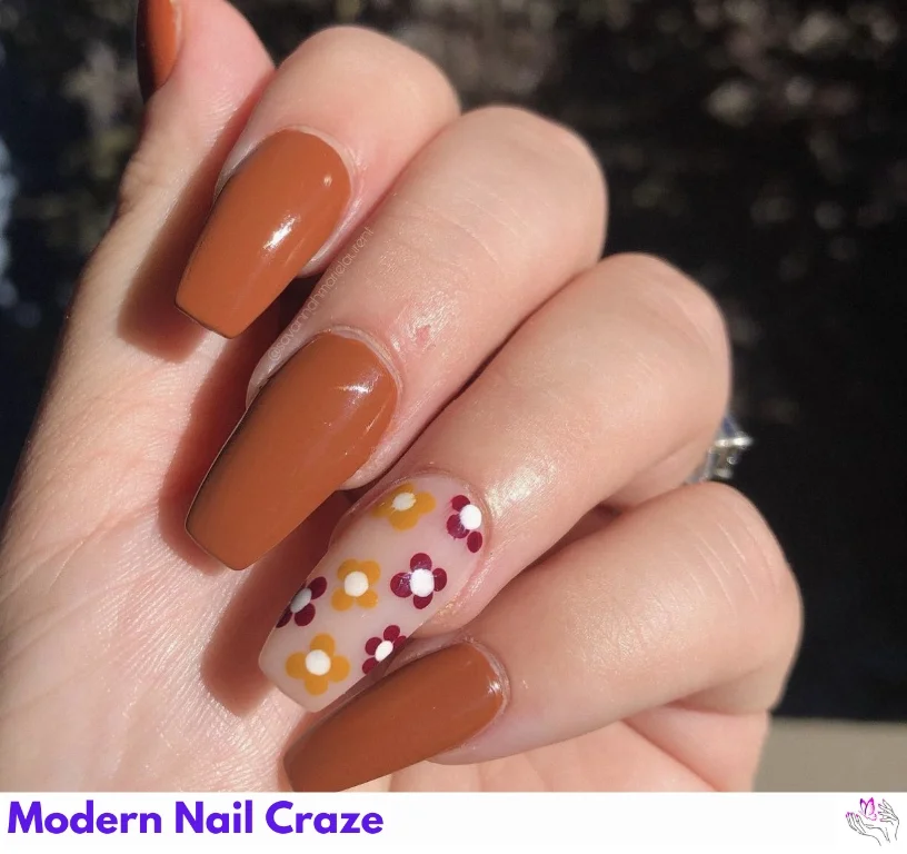 Fall burnt orange nails with a single floral accent on a solid-color base.