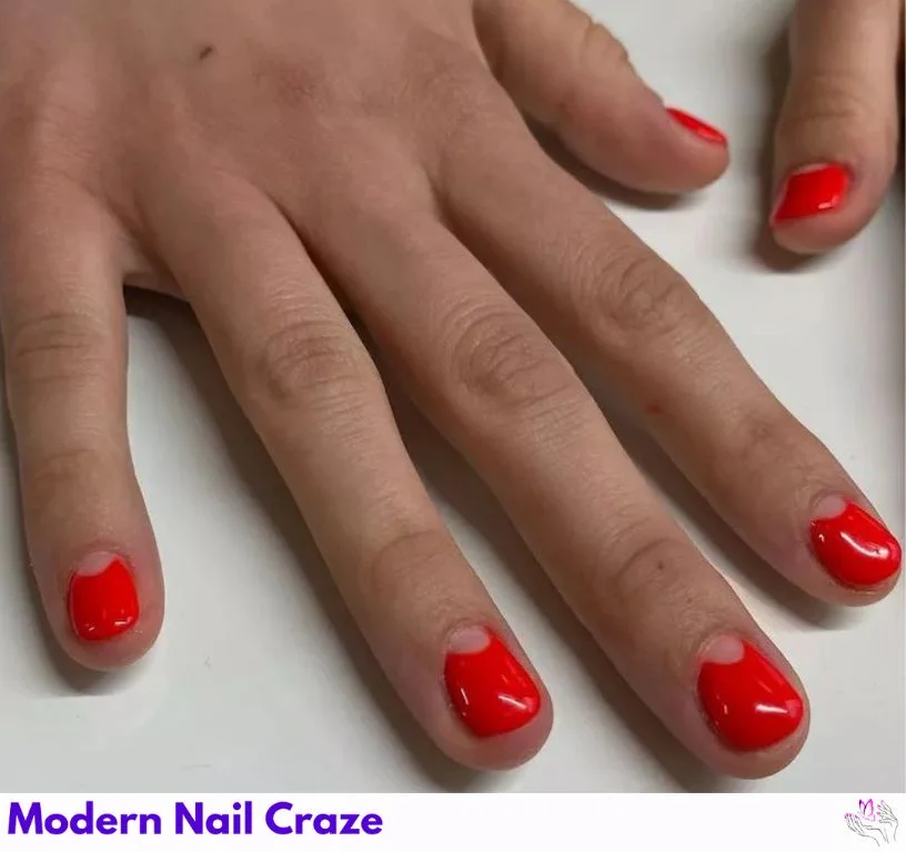 Red-orange manicure with negative space half-moon nail design